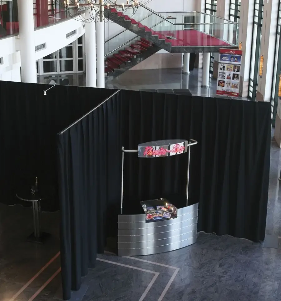 Cloison de rideaux noirs pipe & drape autour d'un stand dans un hall d'exposition